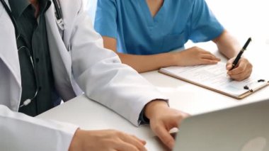 Hastane masasında birlikte çalışan ve tıbbi tedavi planlayan çeşitli profesyonel sağlık görevlileri. Takım çalışması başarılı hastalıklara ve hastalıklara yol açar. Ağır çekim. Katı.