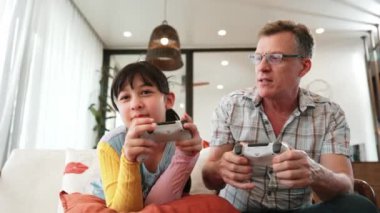 Granddaughter teaching grandfather play console game, entertainment hobby. Old senior use technology communicate with new generation kid cross generation gap strengthen family bond. Divergence.