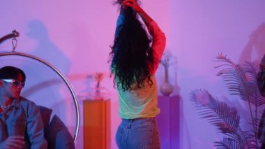 İspanyol hipster renkli kıyafetler giyer ve serbest stil müziğe el sallar. Profesyonel break dansçı neon ışıklarıyla ve modern stüdyo arkadaşlarıyla coşkuyla dans ediyor. Mutluluk.