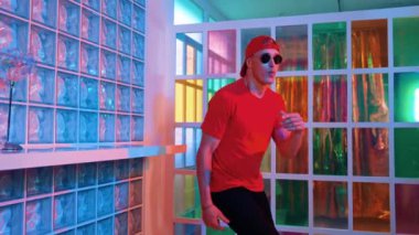 Komik break dansçı kameraya bakarken hiphop 'a doğru serbest adım atıyor. Çılgın mutlu hipster dans edip sokak dansı yaparken Led ışığında günlük kıyafet ve güneş gözlüğü takıyor. Mutluluk.