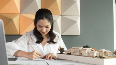 Mimari model, dizüstü bilgisayar ve planla not alırken kalem kullanarak ev modelini ölçen genç ve güzel mimar mühendisinin portresi. Yaratıcı iş tasarımı konsepti. Yönlendirici.