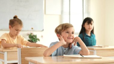 Sınıfta okuyan çeşitli çocuklarla çevrili beyaz bir çocuk öğretmenine soru sorup cevap verdiği için elini kaldırıyor. Mutlu öğrenci birlikte çalışıyor, oy veriyor, gönüllü oluyor, hocayı arıyor. Pedagoji.