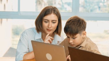 Akıllı çocuk kodlama programı ya da BTMM Teknoloji sınıfında öğrenme programı. Profesyonel öğretmen ekrana bakıp dijital kodu kontrol ederken, beyaz öğrencilerin programlama sistemi üzerine çalışmaları. Etkinlik.