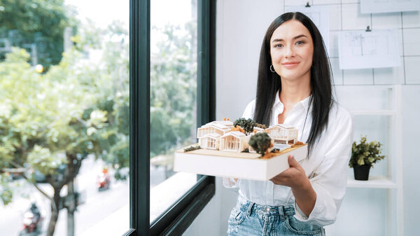 Крупный план квалифицированного молодого красивого кавказского архитектора лифта дом модели левой и правой стороны, чтобы проверить и сосредоточиться на проверке ошибок точки в современном офисе с чертежом. Непорочный.