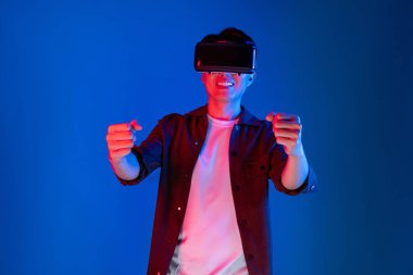 VR kullanan zeki bir oyuncu araba yarışlarında araba sürerken yeni dünyaya dönüyor mavi neon ışıklı duvar bağlantılı fütüristik teknoloji sanal gerçeklik meta 'sını izole ediyor. Entrika.