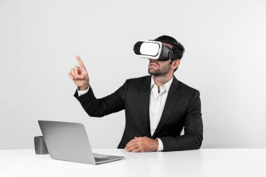 Bilgisayarla masada otururken ve VR gözlüğü takarken veri analizine bakan yetenekli bir iş adamı. Proje yöneticisi sanal gerçeklik sistemini kullanarak ya da metaevrende bağlantı kurarak çalışıyor. Sapma.