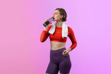 Vücut uzunluğunun tamamı atletik ve sportif genç bir kadını havluyla ve içme suyuyla izole edilmiş arka planda egzersiz yaparken çekilir. Sağlıklı aktif ve vücut bakımı yaşam tarzı.