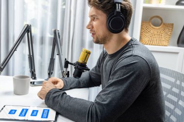 Kulaklık takan bir yayıncı radyo programındaki dinleyicilerle canlı yayında sorun tavsiyesinde bulunuyor. Sosyal medya, modern stüdyo işyerindeki mikrofon ekipmanlarının etrafını sardı. Varsayım.