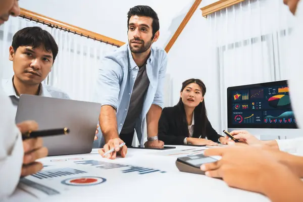 Stock image Analyst team utilizing BI Fintech to analyze financial data at table in meeting room. Businesspeople analyzing BI dashboard power for business insight and strategic marketing planning. Prudent