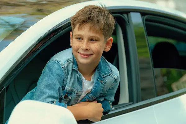 stock image Excited and happy young little boy with smile on his face show up on car window while driving, playful and cheerful expression while on the road trip traveling by car during summertime. Perpetual