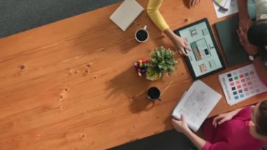 Renk paletinden renk seçmek için birlikte çalışan iş adamlarının üst düzey hava görüşü. İşadamı logo grafiğine bakarken pazarlama ekibine tablet kullanarak yönetici fikri sundu. Sempozyum.