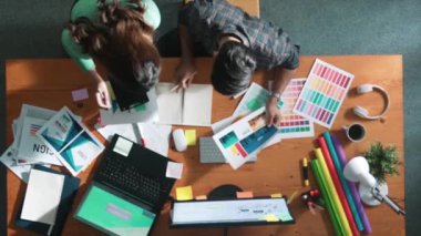 Akıllı tasarımcının renkli paletlerden renk seçmesine yardım ederken yukarıdan aşağı görünümü. Dizüstü bilgisayardan logoya bakarken birlikte çalışan ve planlayan iş adamlarının hava görüntüsü. Sempozyum.