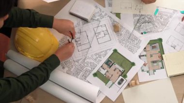 Mimari belge, ölçüm aracı ve ahşap blokların modern ofiste etrafa saçıldığı bir masa üzerinde yapı inşaatı ile ilgili mimar ve güvenlik mühendisi tartışması. Tanımlama.