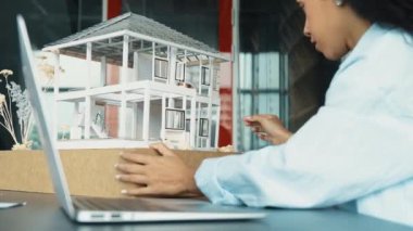 Laptop analizi ev modeli yapısını kullanan İspanyol mimar el mühendislerinin yakın çekimi. Proje yöneticisi dizüstü bilgisayarda yazarken ev modeli inşaatını kontrol ediyor. Tasarım konsepti. Yönlendirici.