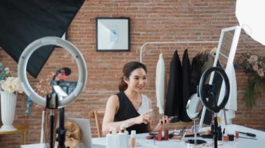 Kadın nüfuzlu kişi canlı yayın yapan video görüntülerini sosyal medya ya da blog üzerinden gözden geçiriyor. Kozmetik stüdyosu ışıklandırmalı mutlu genç kız çevrimiçi pazarlama oturumu yayını için..