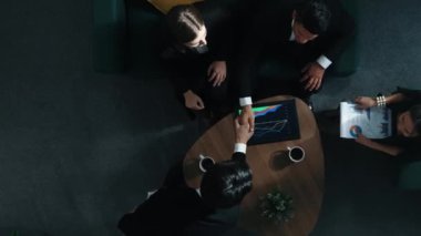 Profesyonel iş adamının yukarıdan aşağıya hava görüntüsü yatırımcıya iş belgesi dağıtırken, yönetici tablet görüntüleme istatistiklerini masaya koydu ve sunumu dinledi. Müdürlük.