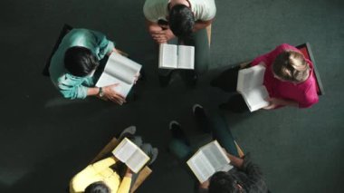 İncil 'i okuyup, kucağında İncil' le daireler çizerek otururken en tepeden aşağı dua manzarası. İnanç, güven ve umut ve sükunetle çalışırken farklı insanların kitaba bakışları. Sempozyum.