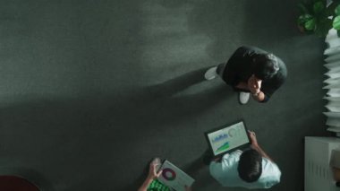 Pazarlama planını düşünen ya da başlangıç projesine yatırım yapmaya karar veren işadamlarına tepeden bakan akıllı profesyonel iş adamları toplantıda tablet kullanarak fikir paylaşımı yapıyorlar. Cemaat.