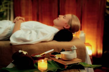 Aromaterapi masajı ambiyansı ya da spa salonu kompozisyon düzeneği bulanık kadınlara odaklı dekor mumları ve spa aksesuarları ile tatil köyü veya otel arka planında keyifli aroma spa masajı yapan. Sessiz.