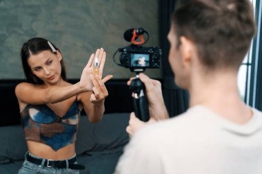 Genç bir kadının sosyal medya için güzellik ve kozmetik dersi videosu çekmesini videoya çeken bir adam. Güzellik blogcusu kameraya gülümserken seyircilere ve takipçilere güzellik bakımını gösteriyor. Açılıyor