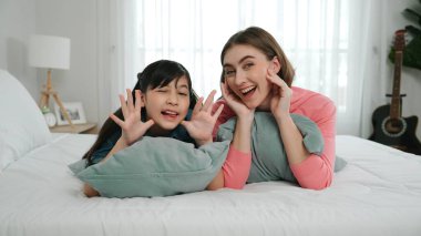 Mutlu Asyalı kız ve akıllı anne kameraya bakarken yatağa uzanıyorlar. Enerjik aile vakit geçirir ve birlikte yatmaya hazırlanır. Sevimli kız ve anne kameraya gülümsüyor sevgi ve şefkat gösteriyorlar. Pedagoji.