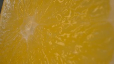 Dilimlenmiş bir portakalın canlı turuncu renginde makro fotoğrafı ve narenciye meyvesinin sulu etinden görülebilir. Portakalın eti dolgun görünüyor. Sıcaklığını gösteriyor. Geliştirilebilir.