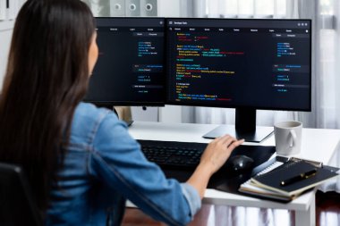 İnternet sitesi uygulamasının kodlama verileriyle birlikte online bilgi yazarak kot gömlek giyen genç Asyalı geliştirici. Güvenlik analizi ile çevrili iki ekran. Taktik.
