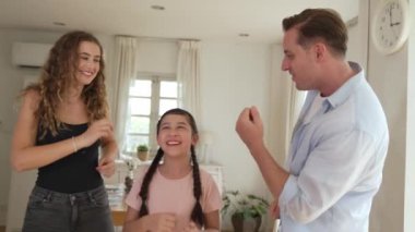 Mutlu aile portresi, gülümseyen sevimli küçük bir kız, sevimli ve neşeli bir ebeveyn ve kızlarıyla birlikte sıcak gün ışığıyla birlikte oturma odasında oturuyorlar. Titiz