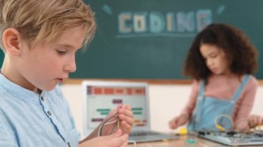 Dizüstü bilgisayar ekranında çalışan çeşitli öğrenci kodlama mühendisliği komut yazılımı ve yapay zeka programlaması yapıyor. Amerikalı kız, erkek makine tamir ederken ekipmanları teftiş ediyor. Pedagoji.