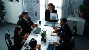 Akıllı iş kadınlarının en üst görüşü çeşitli iş adamlarına satış tablosunun arttığını gösterirken, bir grup farklı iş adamı da masada belgelerle hisse yatırım verilerini dinleyip analiz ediyor. Müdürlük.