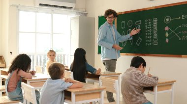 Öğrenci ödevlerine bakarken sınıfta yürüyen yetenekli bir öğretmen. Sınav yaparken ya da sınıfta ödev yaparken akıllı çocuk defterini kontrol eden profesyonel bir eğitmen. Pedagoji.