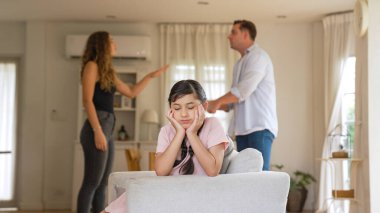 Sinirli ve mutsuz genç bir kız oturma odasında ebeveyninin tartışması yüzünden gerginliğin ortasında kanepede oturuyor. Sağlıksız ev hayatı ve travmatik çocukluk depresyon senkronlarına dönüşür.