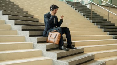 Başarılı bir iş adamı merdivenlerde otururken başarılı bir projeyi kutluyor. Akıllı proje yöneticisi yeni bir iş buluyor, terfi alıyor, telefonla arkadaşlarını ararken satışları arttırıyor. Sevinçli..