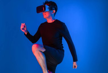 Zeki sporcu VR giyip tüm vücudunu mavi neon ışıklı arka plan üzerinde gererek dijital fütüristik teknoloji sanal gerçekliğini egzersiz konseptine bağlıyor. Entrika.