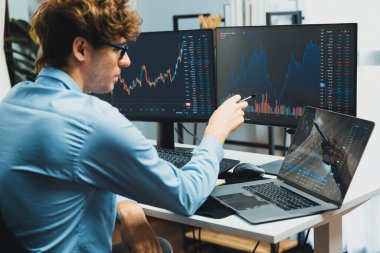 Genç yatırımcı, dinamik döviz kurunu dizüstü bilgisayarda ve bilgisayar ekranındaki dinamik piyasa grafiğinde, gerçek zamanlı olarak modern ev ofisteki finansal teknoloji verilerini analiz ederek gösteriyor. Toplayıcı.