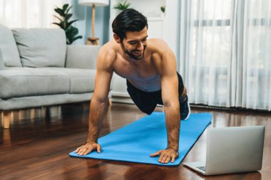 Atletik ve sporcu adam, evdeki fiziğe ve sağlıklı spor yaşam tarzına uygun vücut egzersizi sırasında spor minderinde şınav çekiyor. Gaiety evde egzersiz eğitimi.
