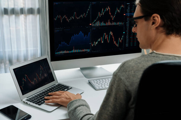 Stressful businessman casual day looking on dynamic stock exchange market graph on pc screen at modern office, analyzing to compare with database computer and laptop at working from home. Pecuniary.
