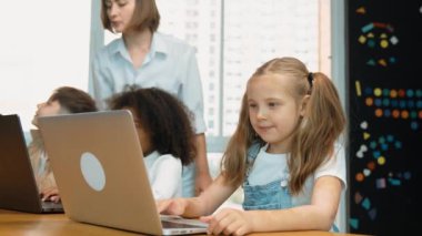 Çok kültürlü bir öğrenci dizüstü bilgisayar kullanarak mühendislik kodları yazarken öğretmen program hakkında açıklama ve öğretim yapıyor. Profesyonel eğitmen BTMM sınıfında programlama sistemini öğrenmeye yardım ediyor. Etkinlik.