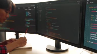 Yavaş çekim arkası yazılım geliştirici mühendisi bilgisayar programlama için birlikte çalışarak hata ayıklama kodunu çözüyor, ofiste monitörde karmaşık algoritmaları çözüyor. Filizlenen