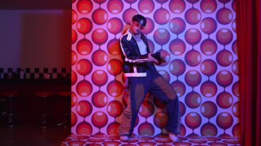 Asyalı break dansçı serbest stile geçiyor ve balon arka planlı kameraya bakıyor. Profesyonel hippi gündelik kıyafet giyer ve gözlük takar. Mutluluk.