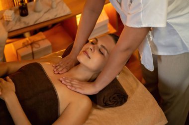 Beyaz kadın müşteri stres önleyici spa masajının keyfini çıkarıyor ve lüks otel ya da otelde sıcak mum ışığında güzellik teniyle eğleniyor. Sessiz.