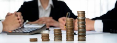 Büyüyen madeni para yığını iş yatırımını ve ekonomik büyümeyi simgeliyor. Finansal hedefe ulaşmak ve maksimum kâr sağlamak için finansal planlama yapan iş adamları. Kurnaz.