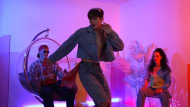 Çok kültürlü bir arkadaş kürsüde otururken Asyalı yetenekli bir dansçı modern müziğe geçiyor. Profesyonel dansçı, hipster takımı tezahürat yaparken ve desteklerken enerjik adımlar atıyor. Mutluluk.