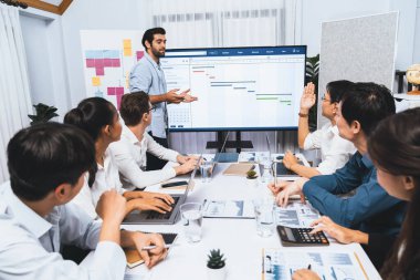 Proje yöneticisi monitörde proje yönetimi yazılım görüntülemesi, proje görevinin ilerlemesini izlemek ve toplantı masasında program planı yapmak suretiyle ekiple iletişim kurar ve işbirliği yapar. Tedbirli