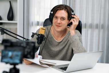 Akıllı yayıncının sunucu kanalı canlı sosyal medya yayını ile dinleyicilere senaryo okuyarak, kulaklık takarak modern ev stüdyosundaki video flamalarını kaydediyor. Bireysel.