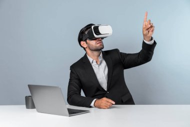 Bilgisayarla masada otururken ve VR gözlüğü takarken veri analizine bakan yetenekli bir iş adamı. Proje yöneticisi sanal gerçeklik sistemini kullanarak ya da metaevrende bağlantı kurarak çalışıyor. Sapma.