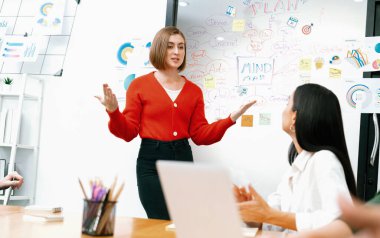 Profesyonel çekici kadın lider, modern iş toplantı odasında beyin fırtınası zihin haritalama istatistikleri ve renkli yapışkan notlar kullanarak yaratıcı pazarlama planını sunuyor. Tertemiz..