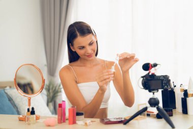 Sosyal medya için güzellik ve kozmetik video içeriği hazırlayan genç bir kadın. Güzellik blogcusu kameraya gülümserken seyircilere ve takipçilere güzellik bakımını gösteriyor. Açılıyor
