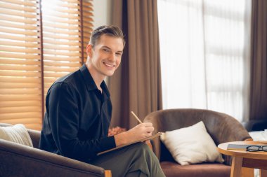 Psikiyatri ofisinde ya da terapi odasında koltukta oturan mutlu ve gülümseyen erkek psikolog portresi. Arkadaş canlısı ve profesyonel ruh sağlığı danışmanı ve terapisti. Açılıyor