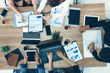 Modern ofisteki iş adamları ve iş kadınlarıyla grup toplantısındaki iş adamlarının en üst düzey görüşü, masada dizüstü bilgisayar, kahve ve belge ile. Kurumsal şirketler uds